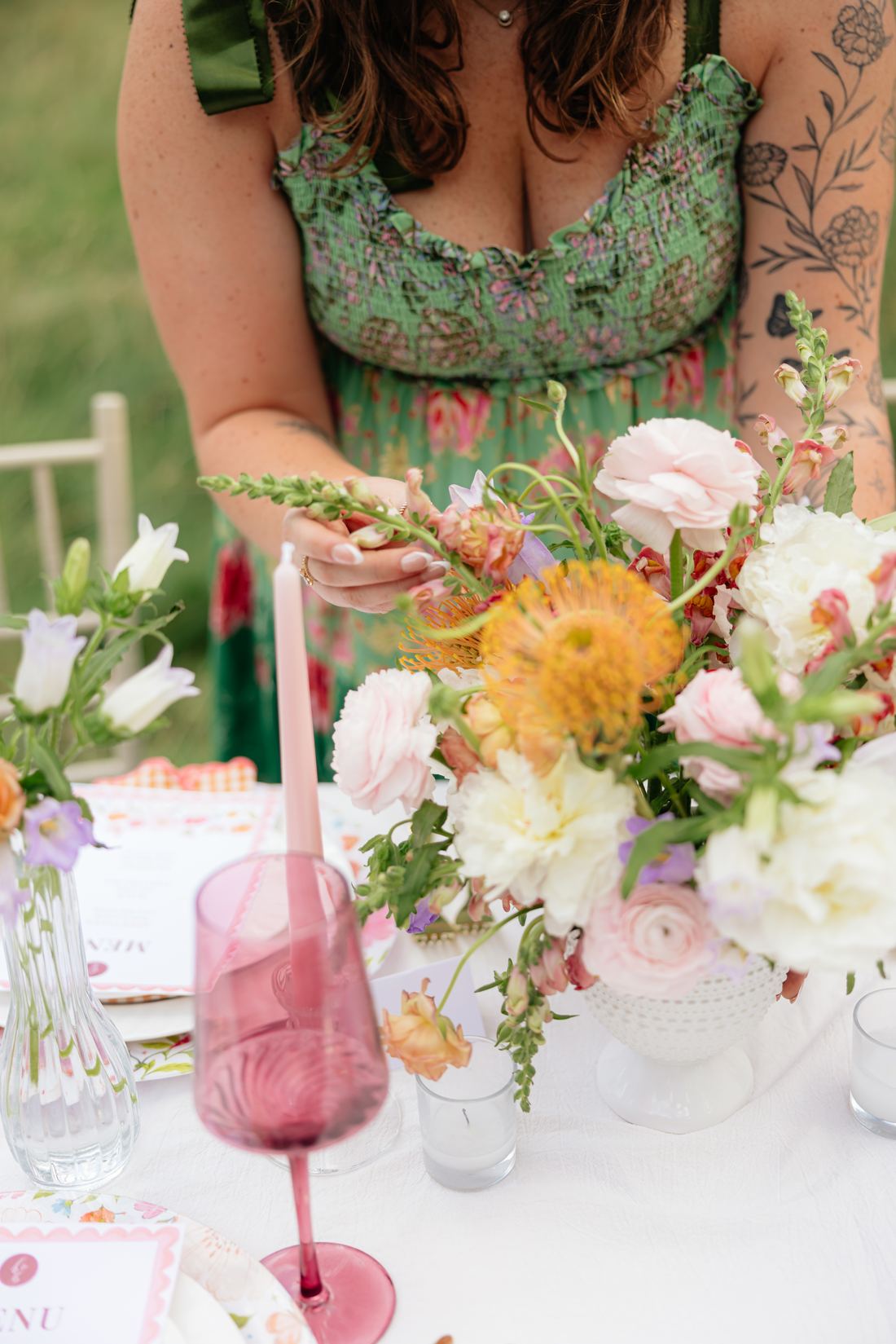 Riley Hogan arranging peach and cream blooms at a table set with pink glassware