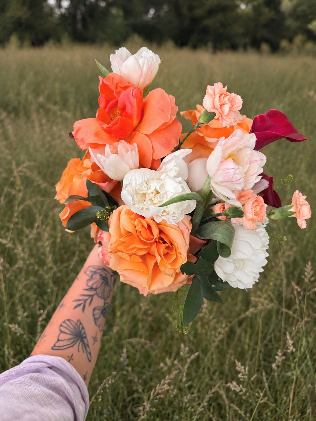 A bouquet of coral roses, cream blooms and peach ranunculus