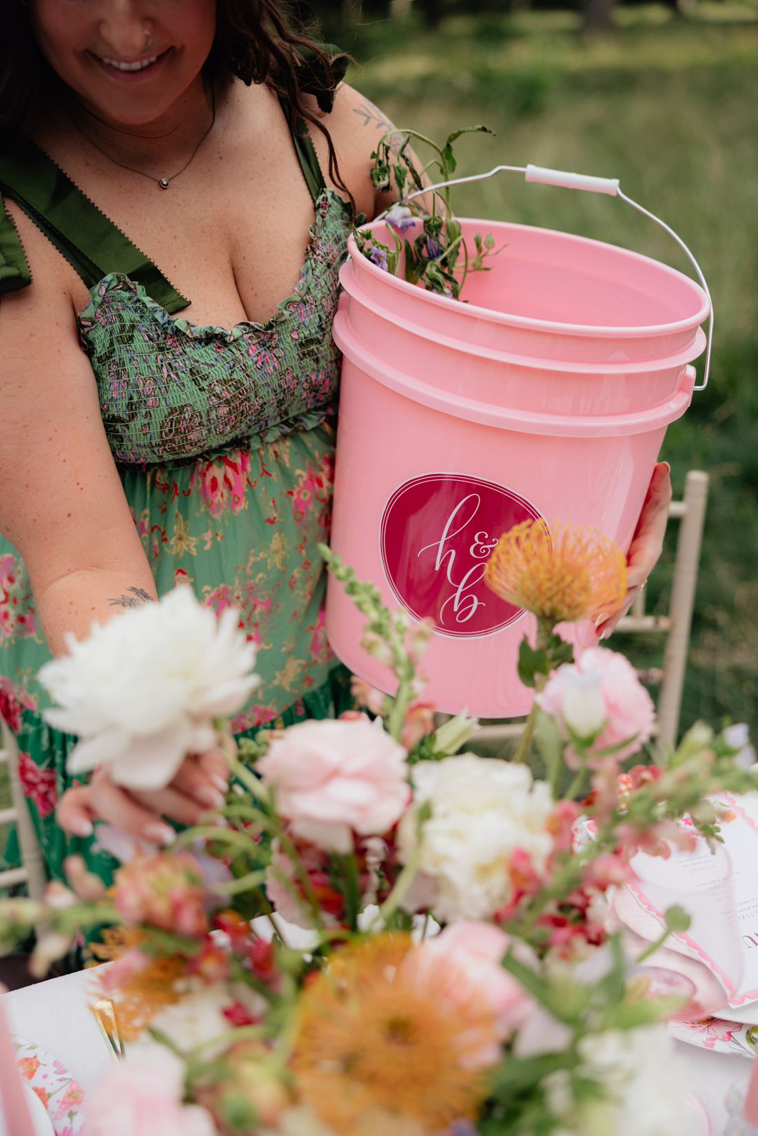 Riley Hogan holding a pink Honey and Bloom flower bucket beside a styled table
