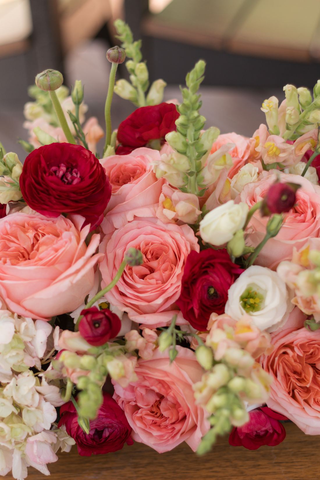 Garden roses, ranunculus and snapdragons in cream, coral and deep red, seen close up