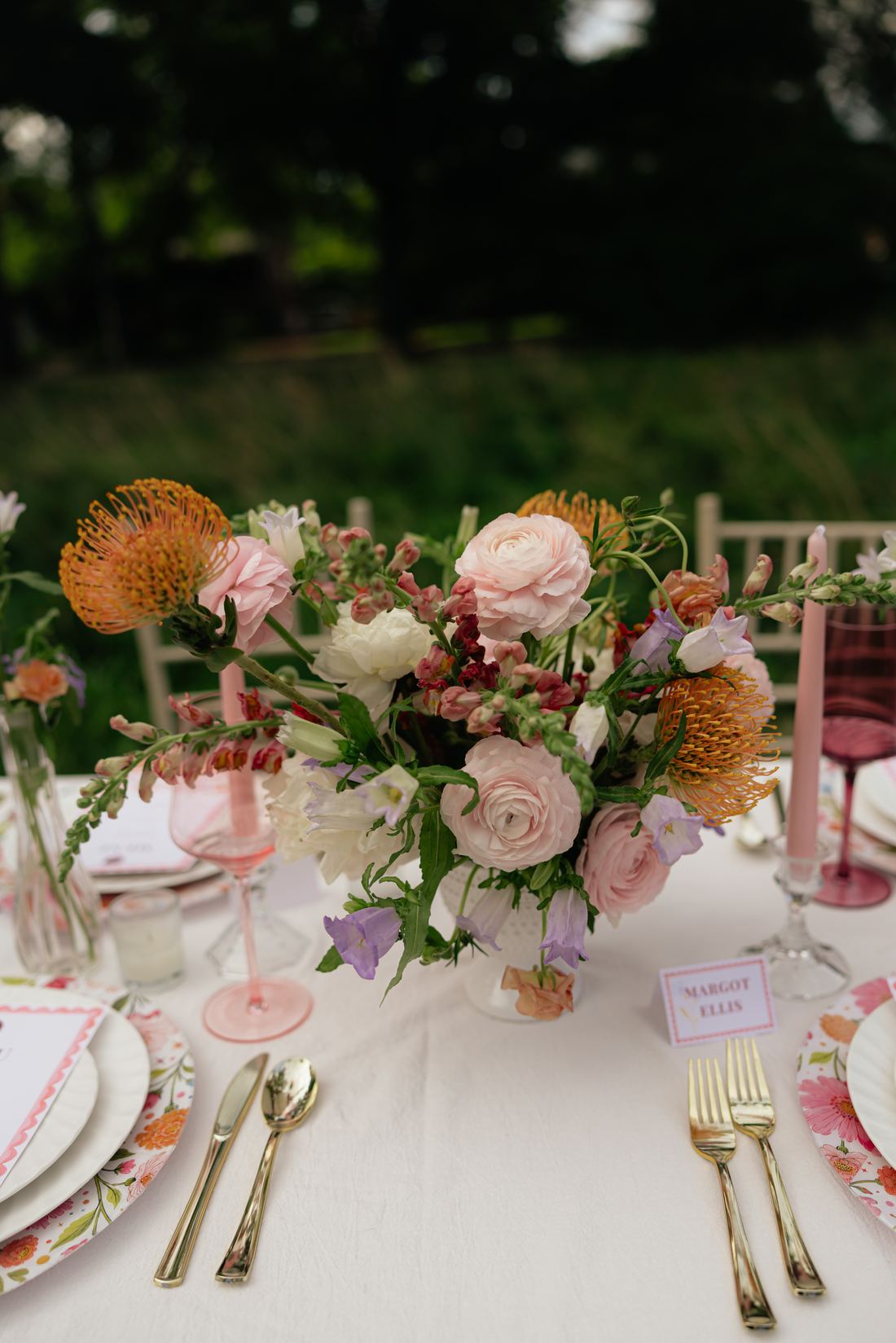 A pink stripe table with a garden centerpiece, bud vases and printed place cards