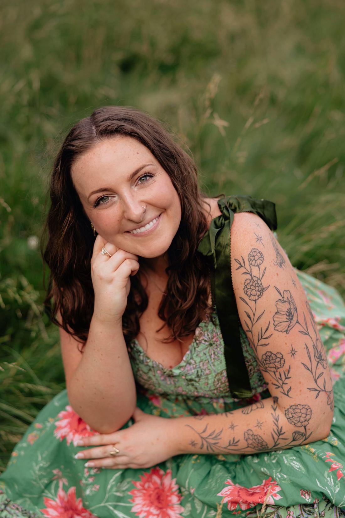 Riley Hogan, founder of Honey & Bloom, seated in a meadow in a green floral dress