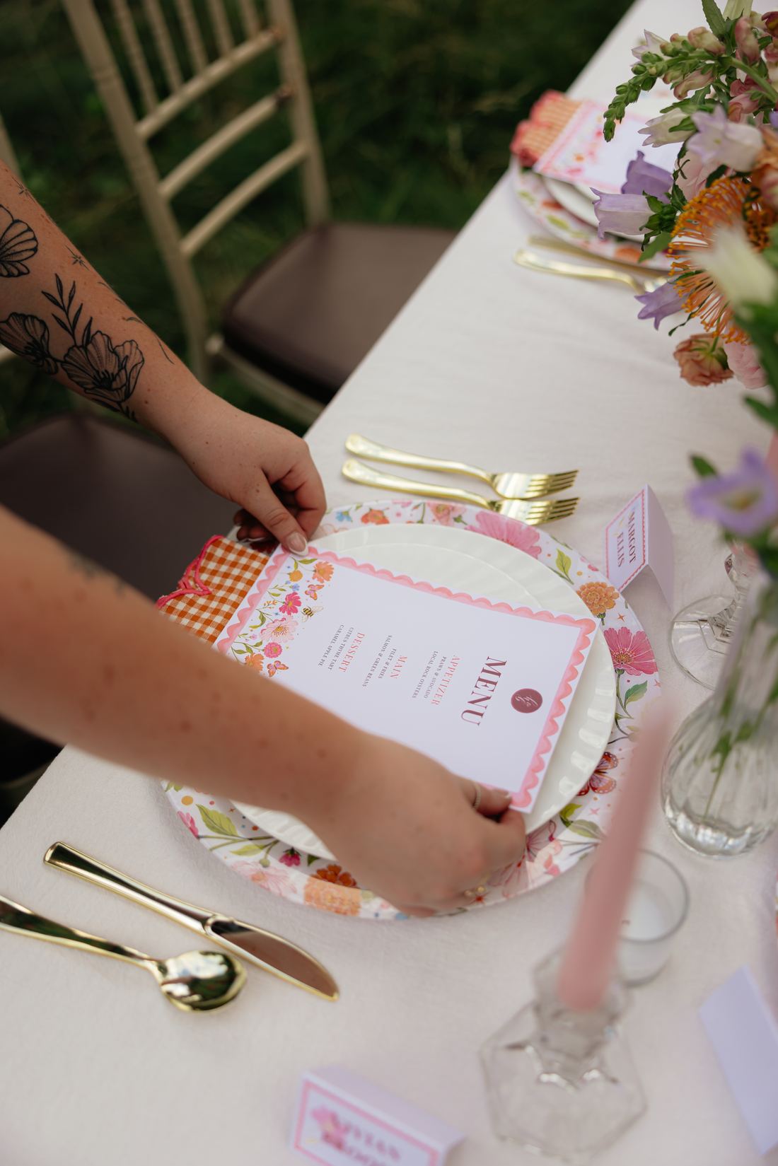 Hands setting a printed menu card onto a floral-printed charger