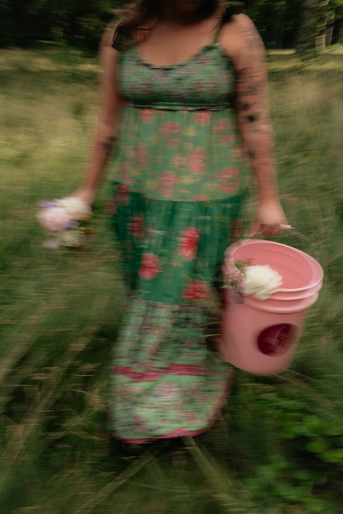 Riley Hogan walking through tall grass carrying a pink flower bucket